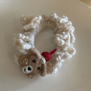 Detailed macro view of handcrafted white knit scrunchie with cute felt bear and red cherry
