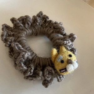 Detailed close-up of handmade brown knit hair tie with yellow wool felt animal decoration