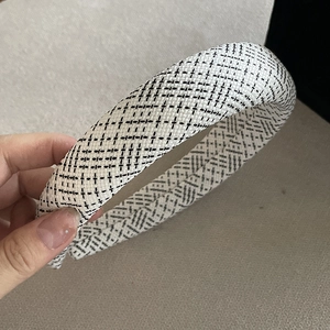 Close-up of black and white tweed sponge headband with thick plaid woven texture