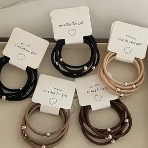 Set of 5 elastic hair ties with metallic beads in neutral tones on white display cards