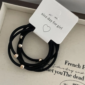 Five-pack set of black elastic hair ties with golden metal beads on a vintage jewelry box