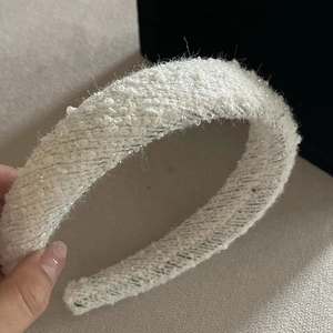 Detail of white bouclé tweed headband with subtle sparkle and thick padded texture