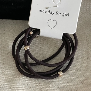 Detail of black elastic hair bands with gold metal beads on a display card holder