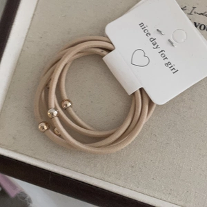 Detail of high-elasticity nude pink hair ties with gold metal bead accents on display card