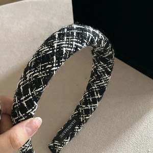 Close-up of black and white tweed headband with gold metallic threads and handmade label