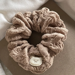 Detail of khaki scrunchie with soft pleated texture and cute white bear patch
