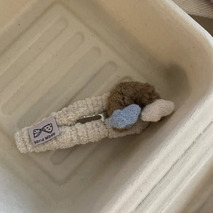Close-up of cute lamb wool hair clip with handmade label and heart decorations