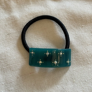 Close-up of a green acetate block with star pattern rhinestones on a black hair tie