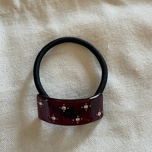 Deep red acetate hair tie with sparkling rhinestones on textured cream linen background