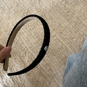 Detail of black knit headband featuring a silver metal badge and soft non-slip lining