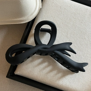 Gros plan d'une pince à cheveux noire mate en forme de nœud avec finition givrée