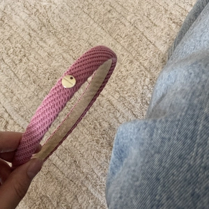 Pink knitted headband with a textured weave and a gold metal logo tag detail