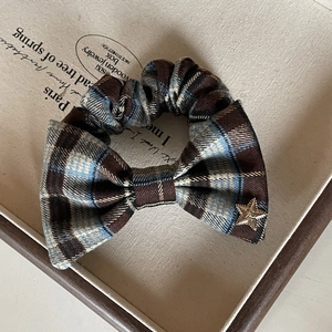 Detail of vintage plaid hair scrunchie with bow knot and golden star metal charm