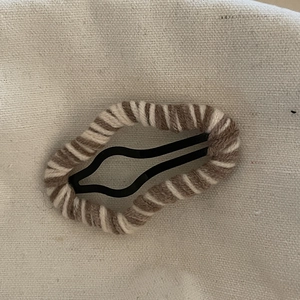 Close-up of cloud-shaped wool wrapped wave BB hair clip on a beige fabric background