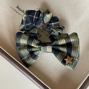 Detail of tartan checkered bow hair scrunchie with golden star metal charm decoration
