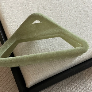 Pince à cheveux triangulaire en velours vert Morandi sur un plateau en lin beige