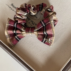 Detail of red plaid bow hair scrunchie with a gold star charm and pleated fabric texture