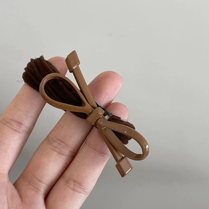 Détail d'un élastique marron avec un nœud papillon creux en résine brillante polie