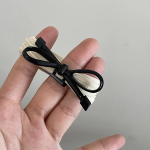 Détail d'un élastique à cheveux nœud en résine noire brillante avec base beige