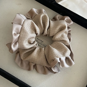 Close-up of champagne satin and textured tweed hair scrunchie with French style