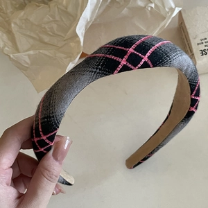 Detail of padded headband featuring black and grey plaid fabric with pink cross-stitch patterns