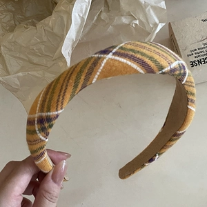 Detail of a thick plaid headband featuring a yellow, green and purple checkered fabric pattern