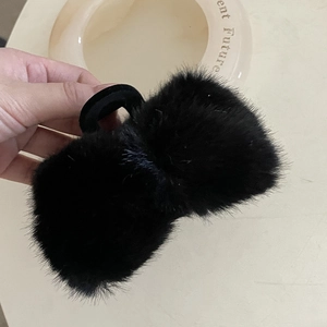 Gros plan sur une pince à cheveux nœud en peluche noire en fausse fourrure douce