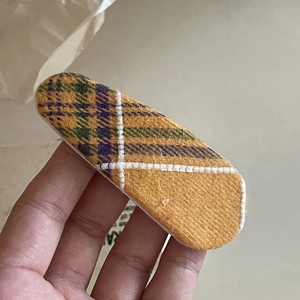 Detailed close-up of yellow plaid fabric hair clip with white cross-stitch quilting texture