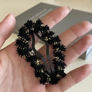 Close-up of black woolen cloud hair clip with golden silk thread and metallic structure