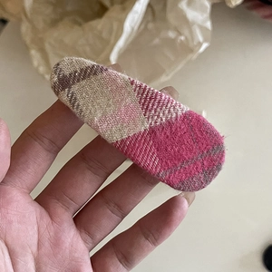 Handheld pink plaid fabric hair clip with a classic checkered pattern for girls