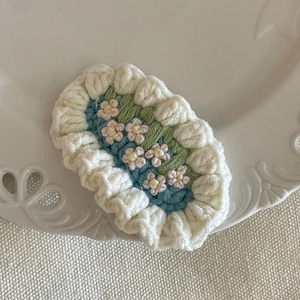 Barrette à cheveux fleurie faite à la main au crochet sur une assiette blanche décorative