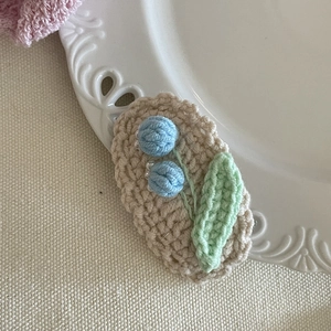 Détail macro de la pince à cheveux au crochet avec fleurs bleues et feuilles vertes
