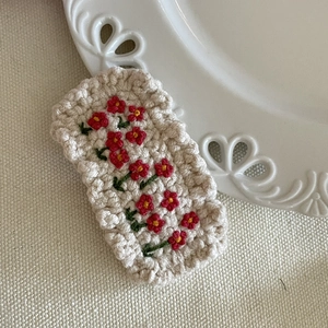 Détail d'une pince à cheveux au crochet faite main avec broderie florale rouge