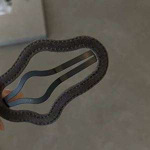 Macro shot of dark grey flocked cloud hair clip featuring wavy metal inner frame and stitching