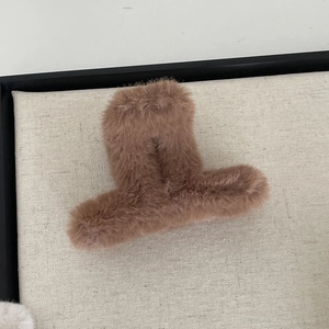 Close-up of large brown faux fur hair claw clip with soft plush texture on grey fabric