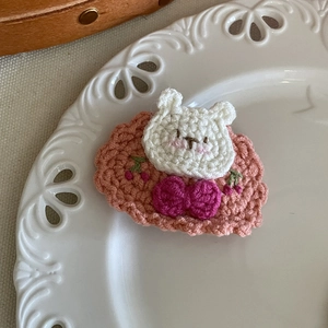 Détail d'une barrette au crochet faite main avec un ours blanc et des cerises rouges