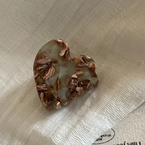 Close-up of heart-shaped acetic acid hair claw clip with amber marble texture