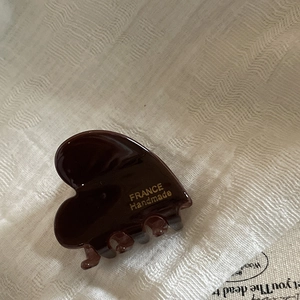 Close-up of heart-shaped acetate hair claw clip with golden handmade lettering detail