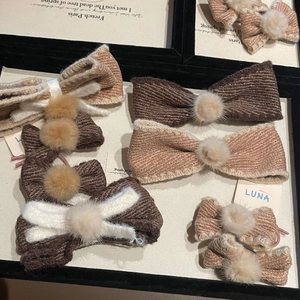 Detailed view of tweed bow hair clips with plush pom-poms in autumn brown color tones