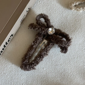 Pince à cheveux noeud en laine d'agneau marron avec cristal sur fond blanc texturé