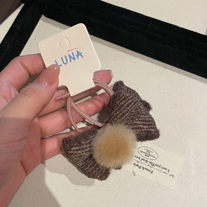 Close-up of brown knitted bow hair tie with soft coffee plush pompom detail