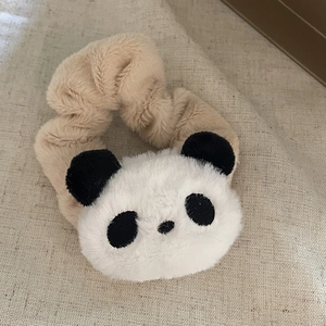 Gros plan sur un chouchou en peluche beige doux avec un petit panda noir et blanc mignon