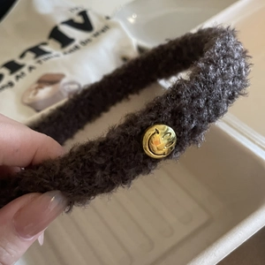 Serre-tête en peluche marron foncé avec un bouton décoratif en métal doré souriant