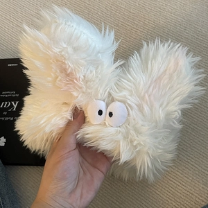 Détail d'un accessoire de cheveux monstre en peluche blanche avec des yeux ludiques