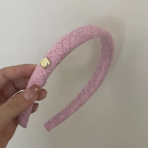 Detail of pink tweed headband featuring a gold-tone square buckle with textured fabric