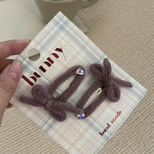 Dettaglio di fermagli viola in maglia con fiocchi e strass a cuore su cartoncino
