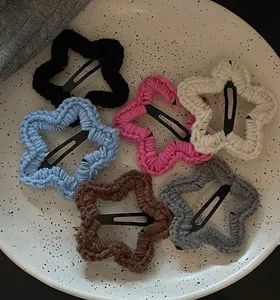 Détail de six pinces à cheveux en étoile tricotées sur une assiette en céramique