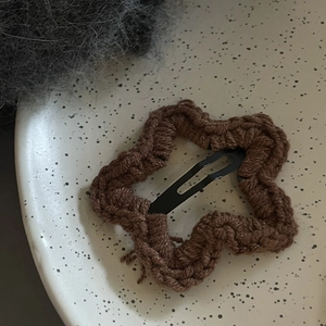 Détail d'une pince à cheveux étoile en tricot marron sur une assiette décorative
