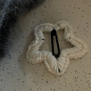 Détail d'une pince à cheveux étoile en tricot crème avec fermoir clic-clac noir