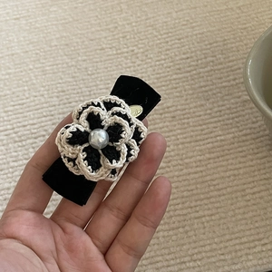 Détail d'une pince à cheveux camélia crochetée avec perle et nœud en velours noir